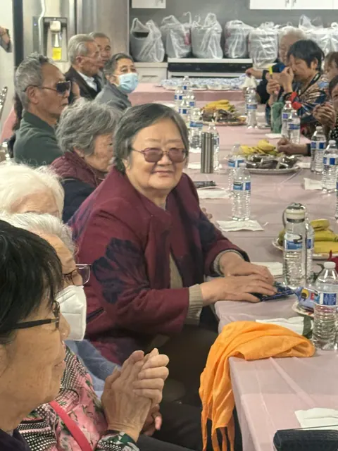 A smiling birthday resident celebrated by applauding neighbors