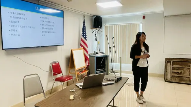 講者站在投影螢幕旁介紹預防詐騙講座內容