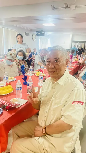 生日會上長者在餐桌前微笑比出勝利手勢