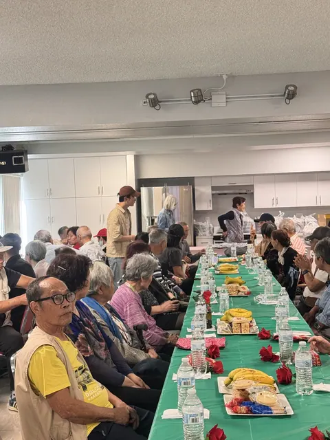 住戶圍坐長桌參加生日會,桌上擺放玫瑰、香蕉與茶點