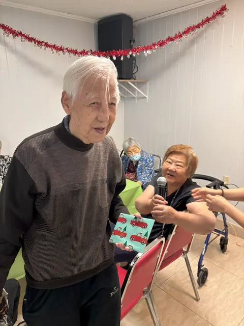 住戶在生日會上開心領取禮物,旁邊的住戶手持麥克風送上祝福