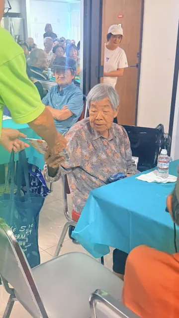 工作人員在餐桌旁與年長住戶互動