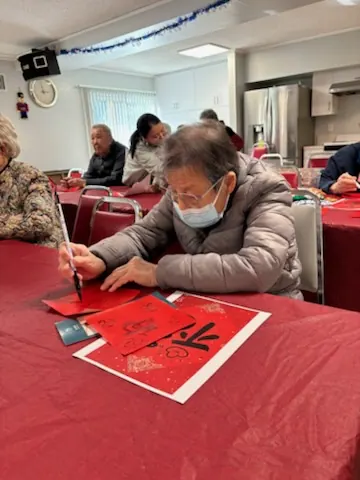 住戶以毛筆在紅紙上書寫福字