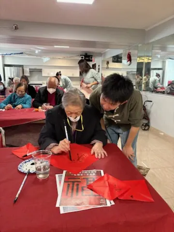 住戶以毛筆在紅紙上揮毫寫福字