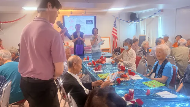 A presenter with a microphone leads residents in a Bingo game